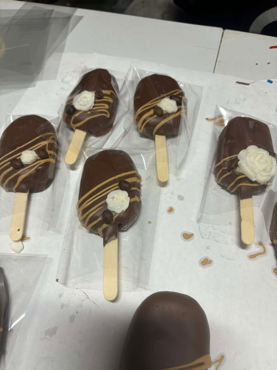 Mocha cakesicles with caramel drizzle, espresso beans, and piped white roses