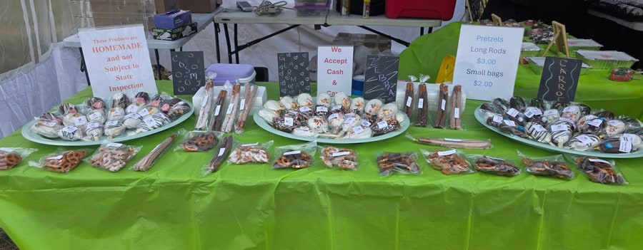 Sugar Rush market table stacked with wrapped cakesicles, pretzel rods, and flavor signs