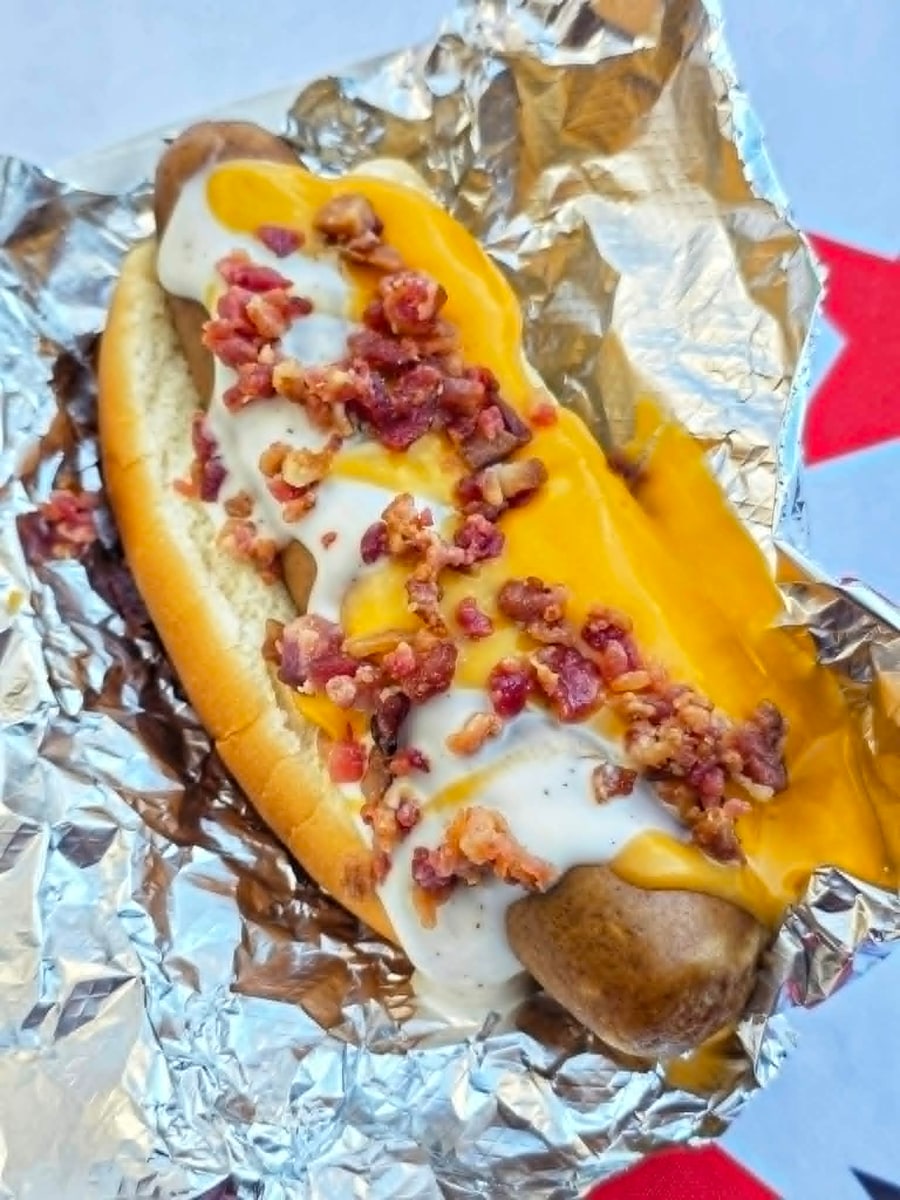 Bacon ranch hot dog with cheddar, ranch dressing, and chopped bacon